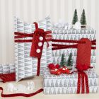 Julegaveindpakning med juletræsmotiv pyntet med pomponer og minifigurer