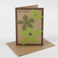 Brunt kort dekoreret med udstansede blade af karton