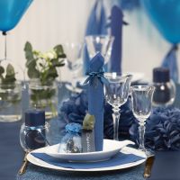 Borddækning og bordpynt i mørk blå med papirblomster, balloner, serviet foldet som tårn og bordkort
