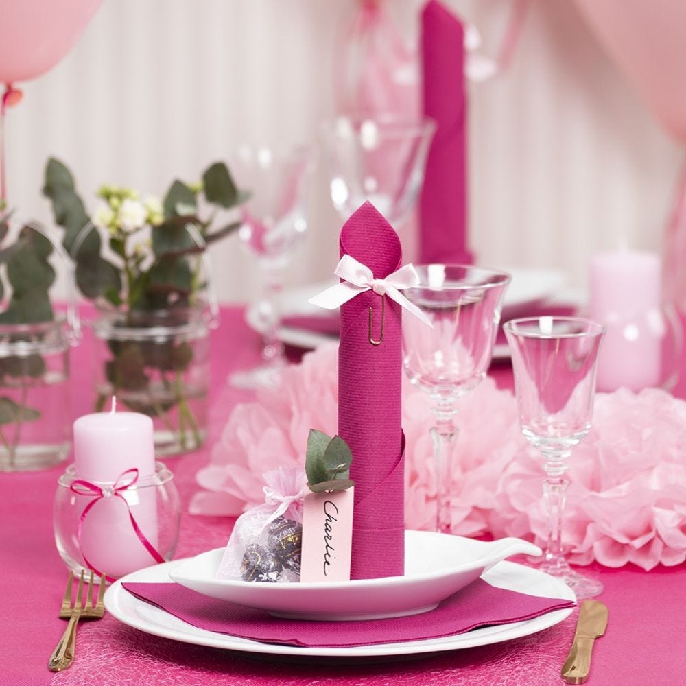 Borddækning og bordpynt i lyserød med papirblomster, balloner, serviet foldet som tårn og bordkort