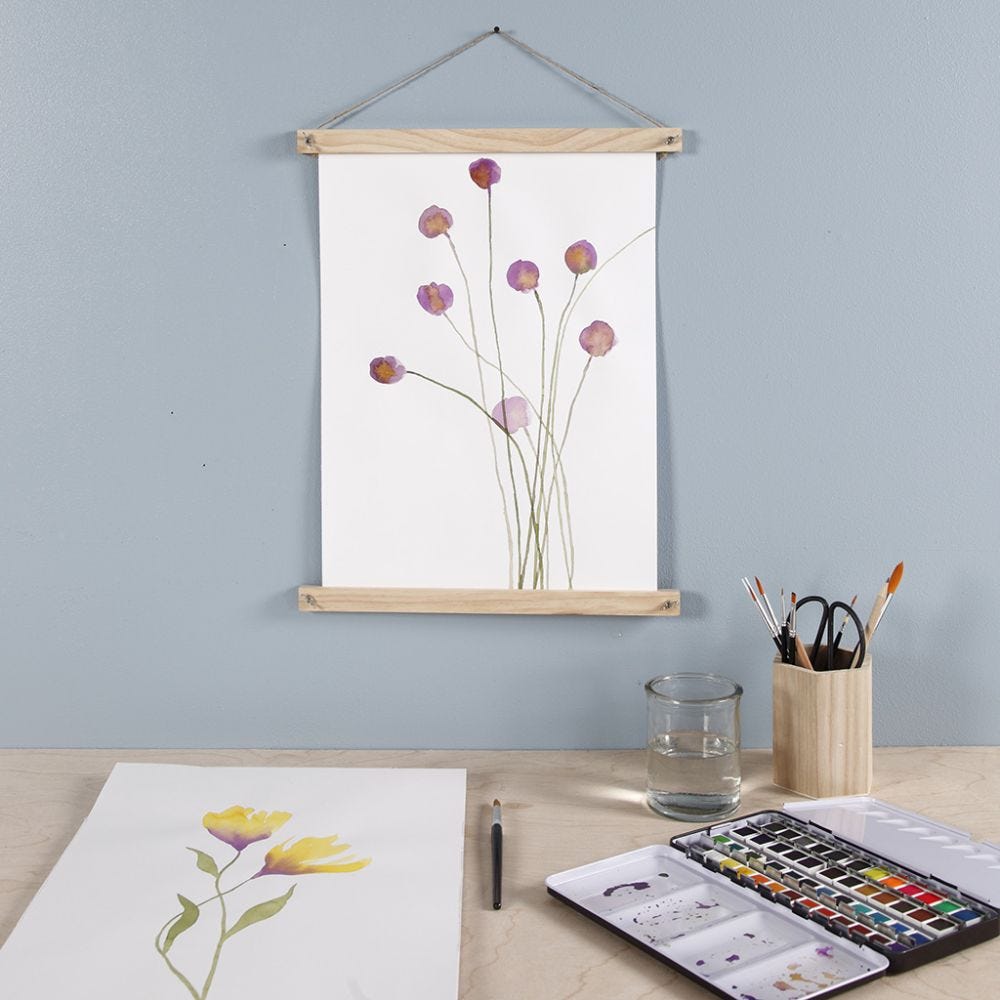 Lilla blomst malet med akvarelmaling og hængt op med plakatliste